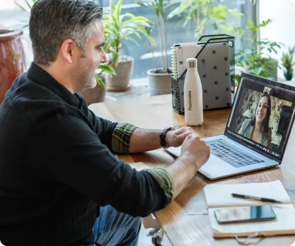 An image of a man in front of a laptop and on a video call with a woman.