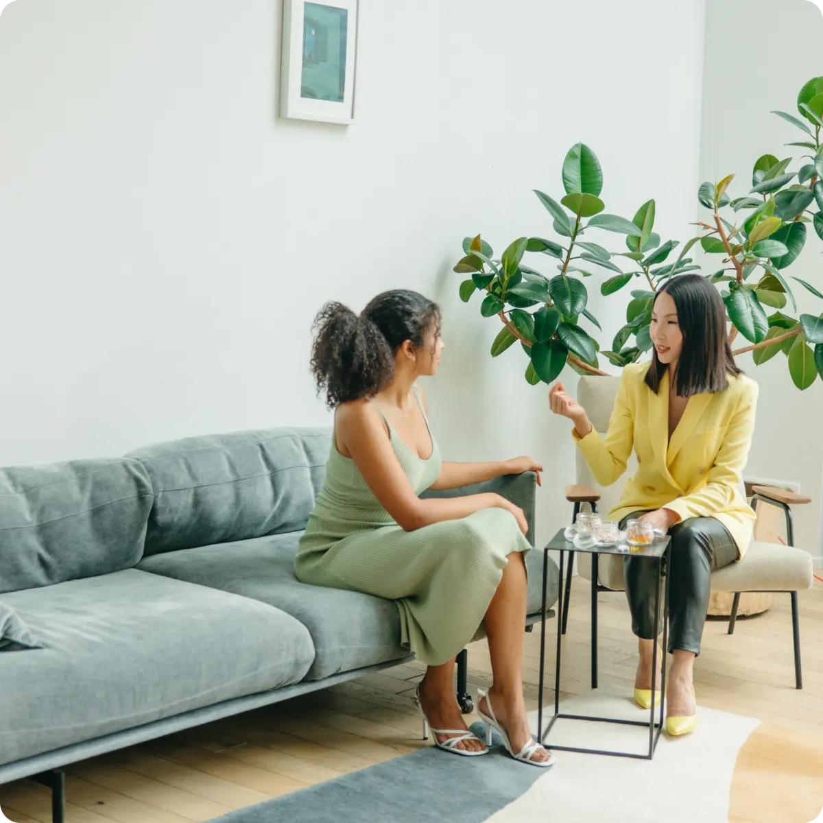 A picture of two women having a meeting with one sitting on a sofa and another one on a chair.