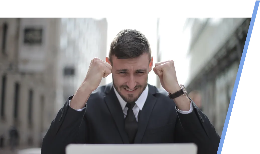 An image of a male realtor in front of a laptop showing excitement and happiness.